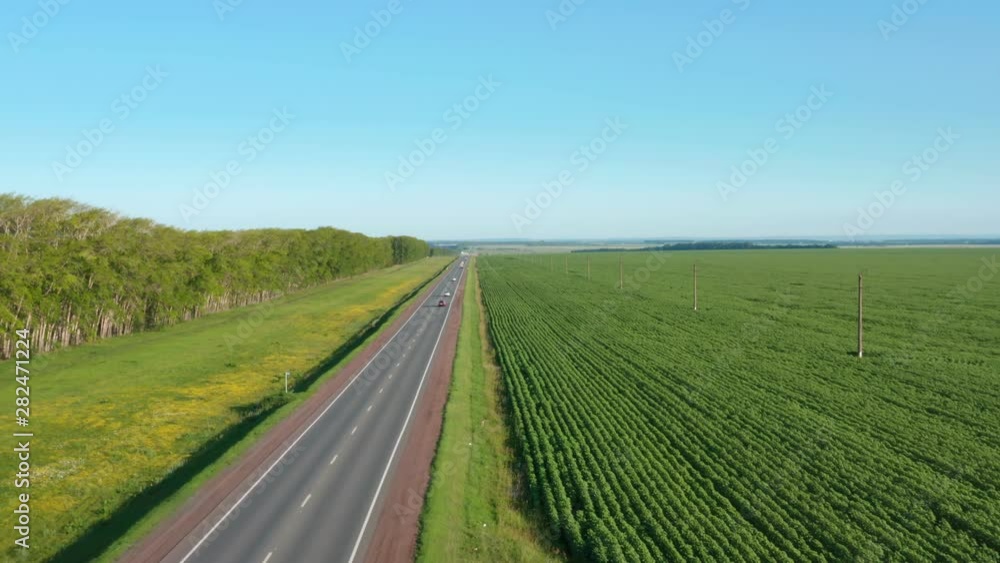 Cars driving on the asphalt road.Highway between the agricultural fields.Aerial pull away shot.Type 1 Cars driving on the asphalt road.Highway between the agricultural fields.Aerial pull away shot.Type 1