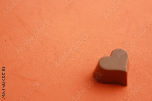 Chocolate bonbon with heart shape in color background