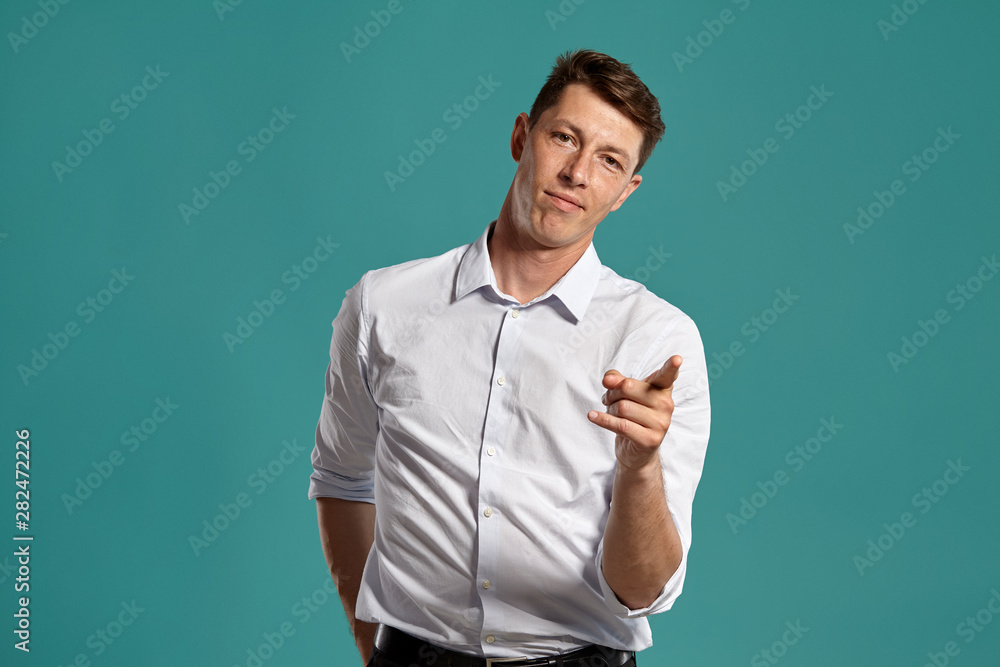 Young man in a classic white shirt is posing over a blue background. Young man in a classic white shirt is posing over a blue background.