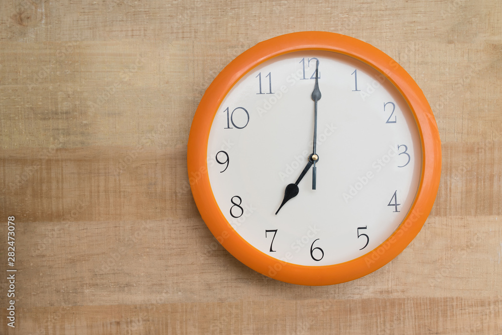 Round wall clock on wooden background. Seven o'clock Round wall clock on wooden background. Seven o'clock