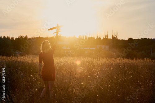 Woman with a toy airplane on the field. Freedom, game, leisure, travel concept.
