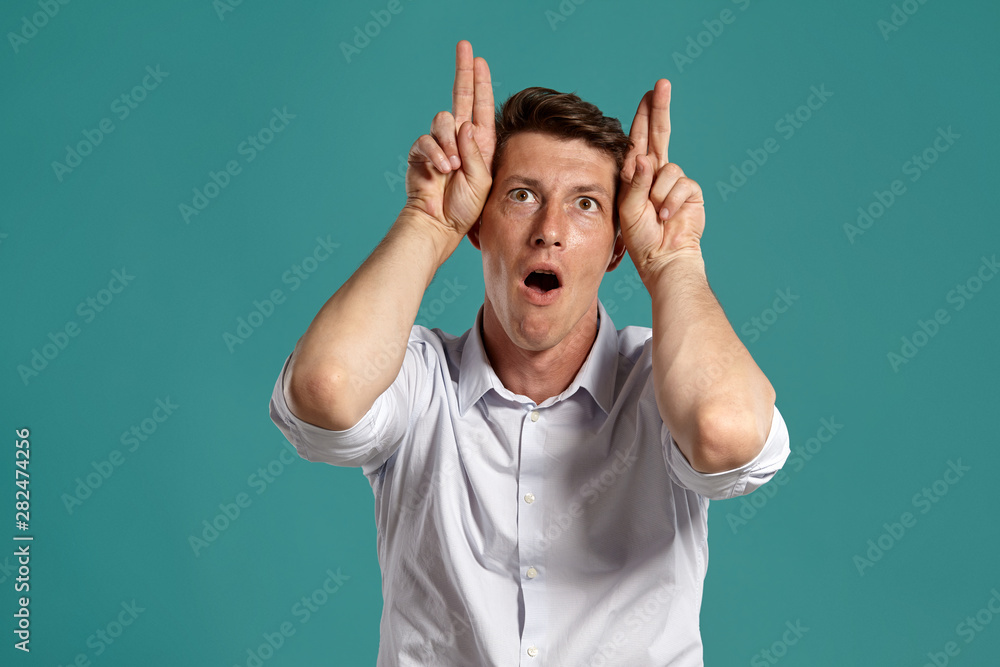 Young man in a classic white shirt is posing over a blue background. Young man in a classic white shirt is posing over a blue background.