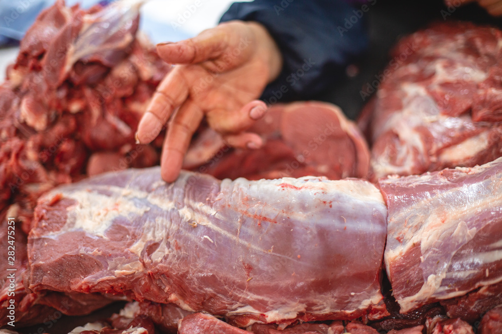 the seller's hands measure a piece of meat to sell to the buyer. selective focus photo from the natural home market with meat horned animals