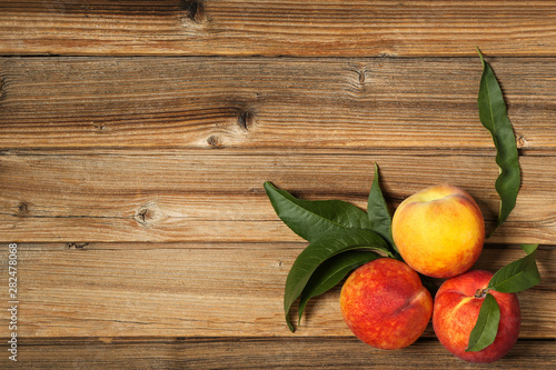 Fresh peaches with green leafs on brown wooden table