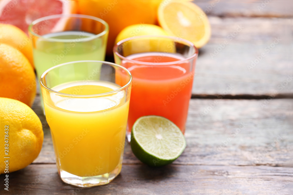 Citrus juice in glasses with fruits on grey wooden table Citrus juice in glasses with fruits on grey wooden table
