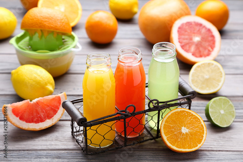 Citrus juice in glass bottles with fruits on wooden table