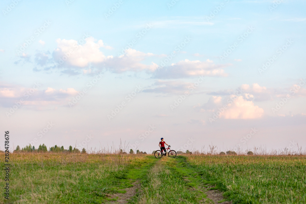 Girl on a bicycle on a background of blue sky and green grass Girl on a bicycle on a background of blue sky and green grass