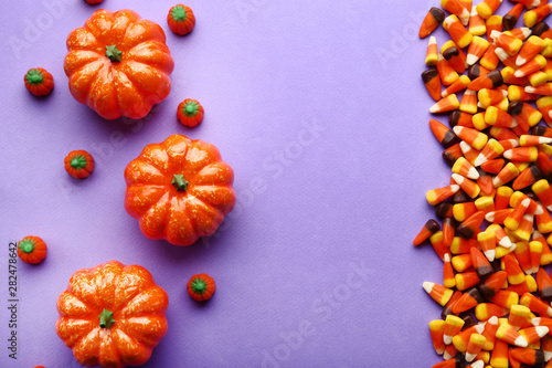 Halloween candy corns and pumpkins on purple background