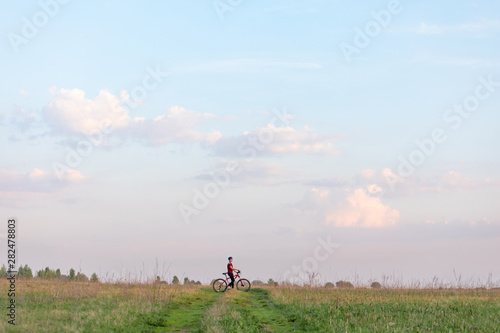 Girl on a bicycle on a background of blue sky and green grass