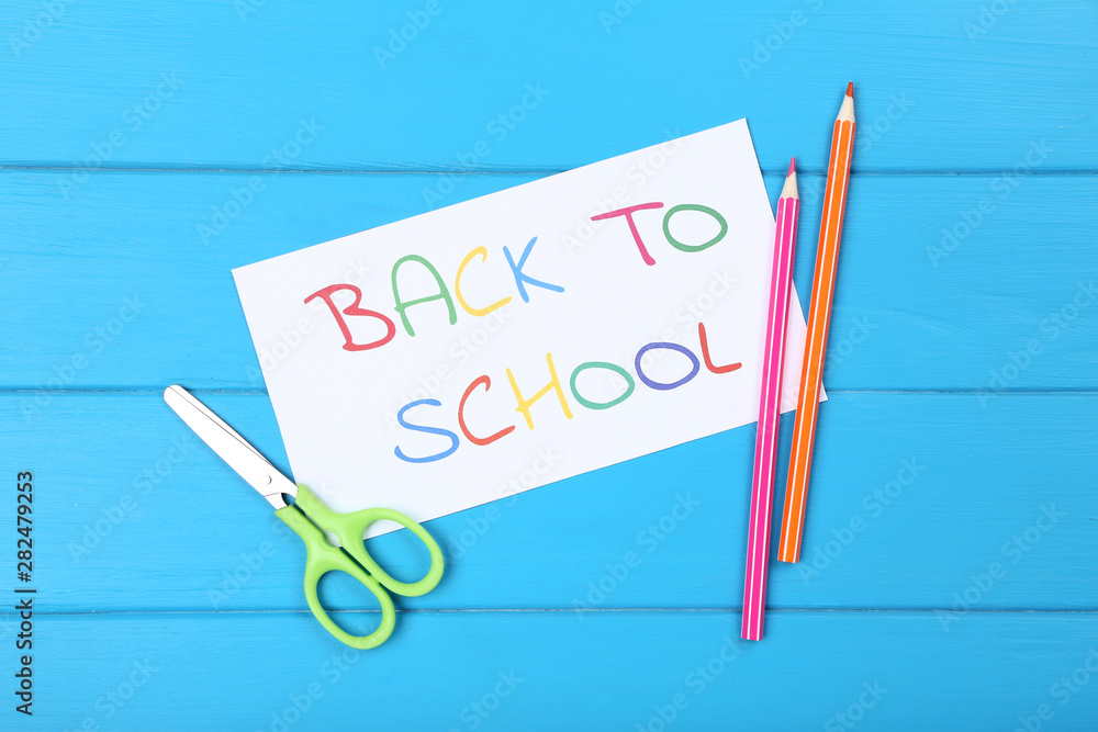Text Back To School with pencils and scissors on blue wooden table Text Back To School with pencils and scissors on blue wooden table