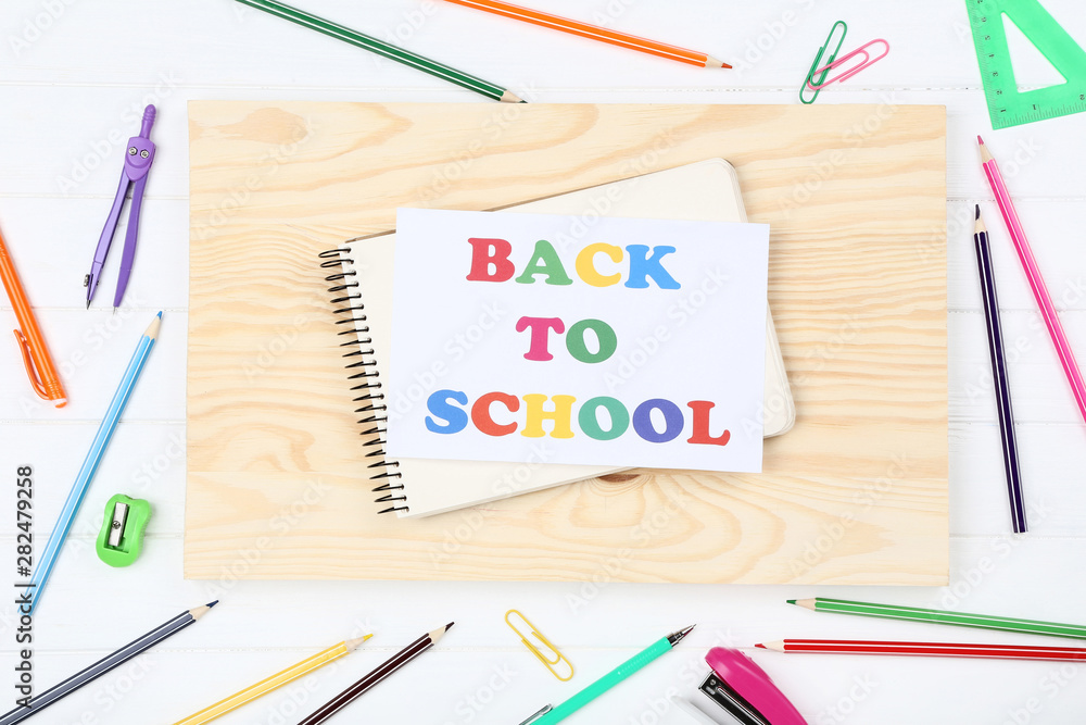 Text Back To School with stationery on white wooden table