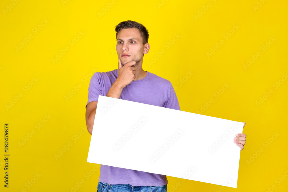 Young man with blank board on yellow background Young man with blank board on yellow background