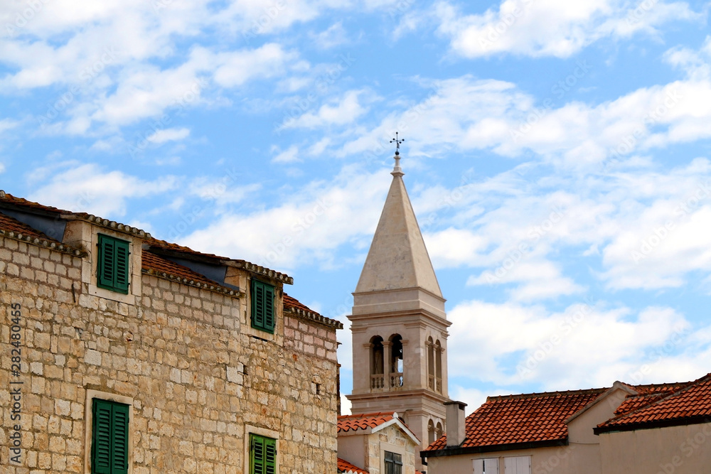 Traditional stone architecture and landmark Church of Mary's Annunciation bell tower in small town Supetar, on island Brac, Croatia. Traditional stone architecture and landmark Church of Mary's Annunciation bell tower in small town Supetar, on island Brac, Croatia.