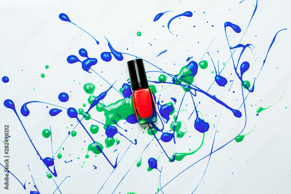 jar of red varnish on a white background with drops of blue and green jar of red varnish on a white background with drops of blue and green