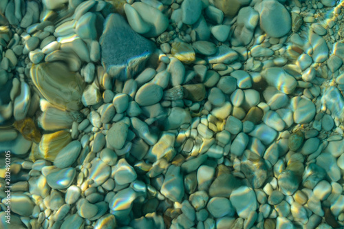 Blurred natural background. Pebbles through the clear sea water.
