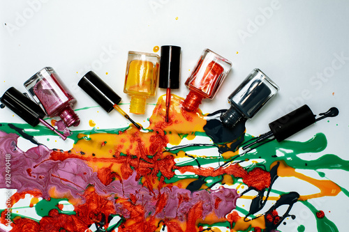 spilled different nail polishes on a white background with cans of varnish
