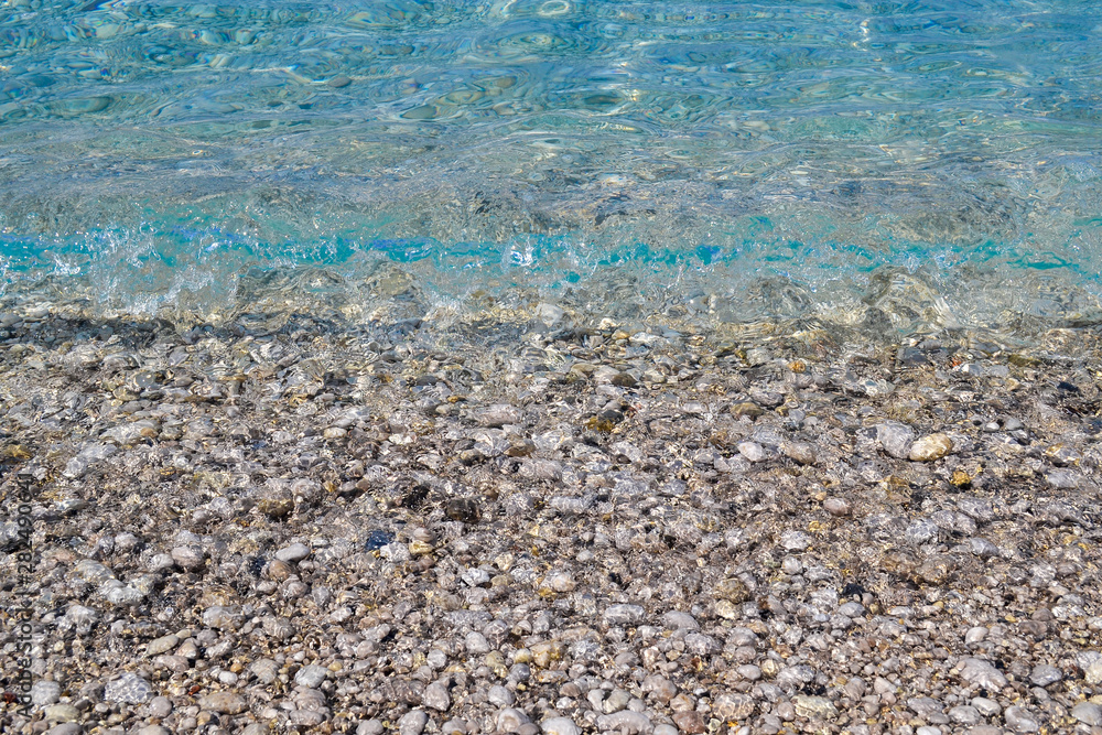 square background image of calm turquoise sea on shingle beach