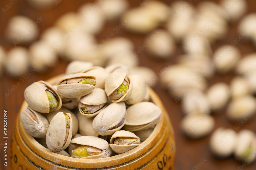 Green pistachios in a wooden jar close up. Healthy and nutritious snack throughout the day with pistachios Green pistachios in a wooden jar close up. Healthy and nutritious snack throughout the day with pistachios