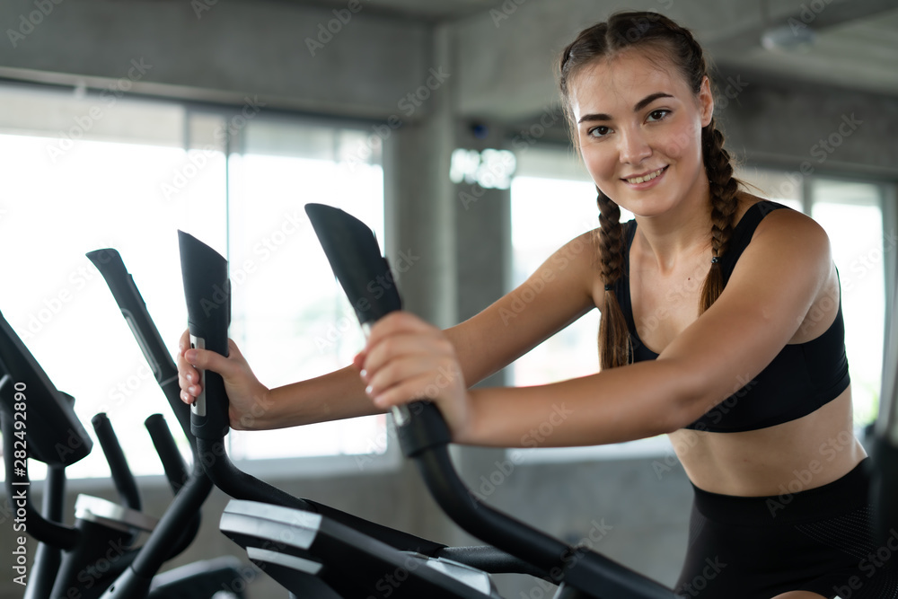Fitness woman in training showing exercises with exercise-machine in gym, fitness concept, sport concept. Young sporty woman stretching at gym. Change for health concept. Fitness woman in training showing exercises with exercise-machine in gym, fitness concept, sport concept. Young sporty woman stretching at gym. Change for health concept.