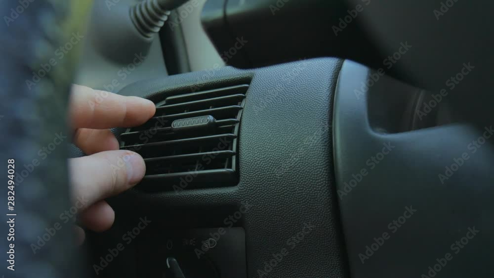 Closeup of hand adjusting air vents to change wind direction inside