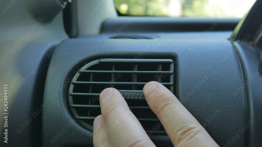 Closeup of hand adjusting air vents to change wind direction inside