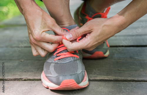 a young white woman ties laces on her running shoes