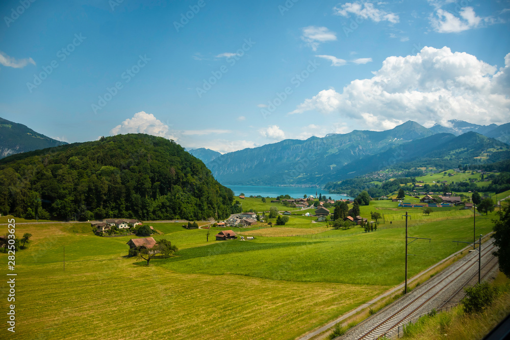 Beautiful swiss landscape. View from the train to a small village near the lake, mountains. Picturesque and gorgeous scene. Switzerland