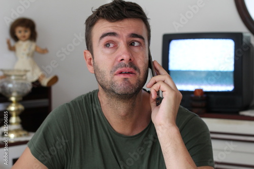 Man crying at home during phone conversation