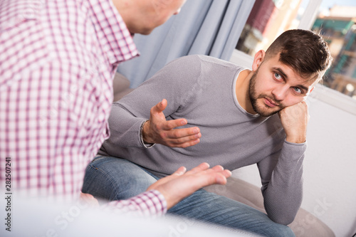 Man having unpleasant talk with colleague on couch