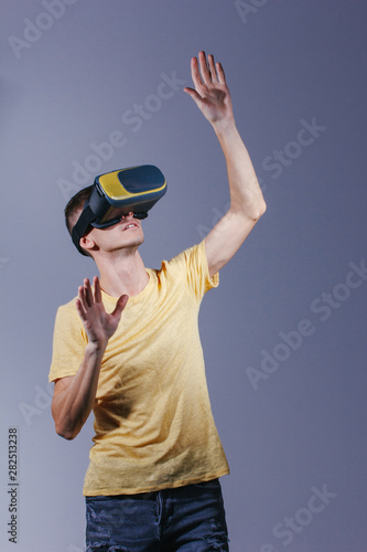 technology, gaming, entertainment and people concept - young man with virtual reality headset or 3d glasses. Studio shot, gray background. © Air_Lady