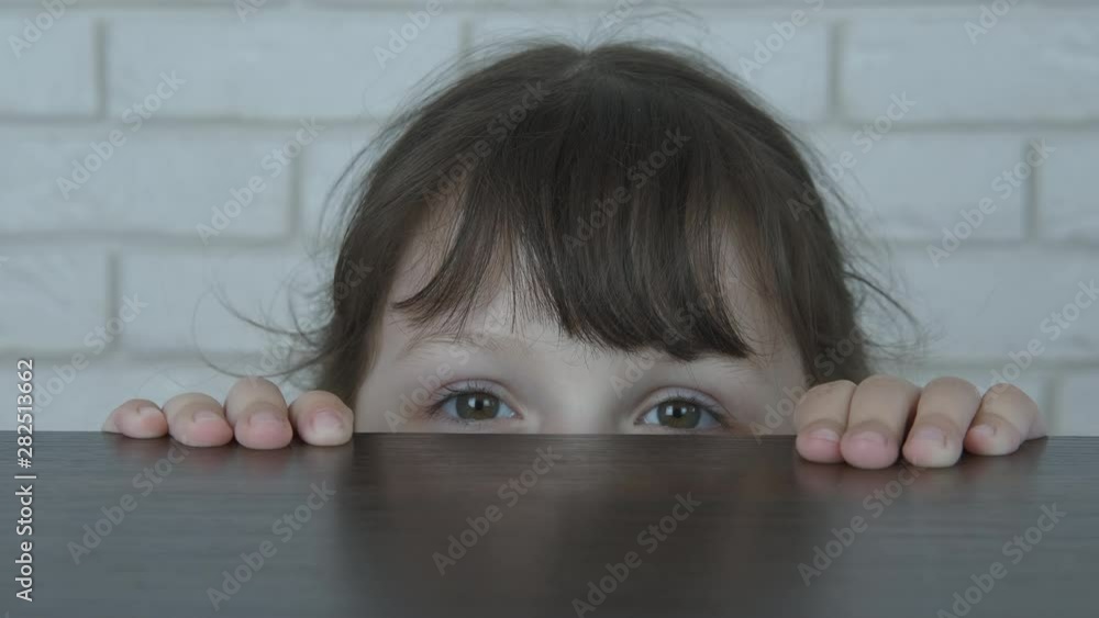 Hide in the room. A cute little girl looks out from under the table. Hide in the room. A cute little girl looks out from under the table.