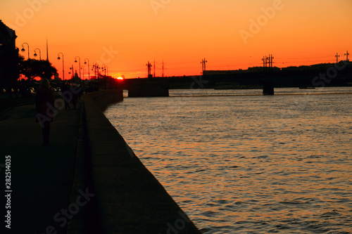 the setting sun over the bridge in the city across the river