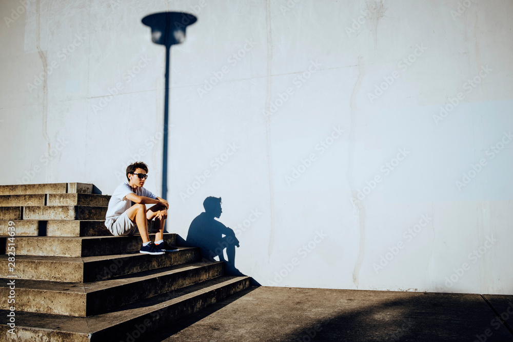 Young male runner resting on sunny urban steps