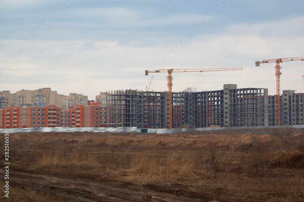Obraz premium Construction site including several cranes working on a building complex.