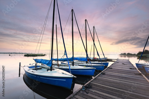 few yachts by pier at dawn