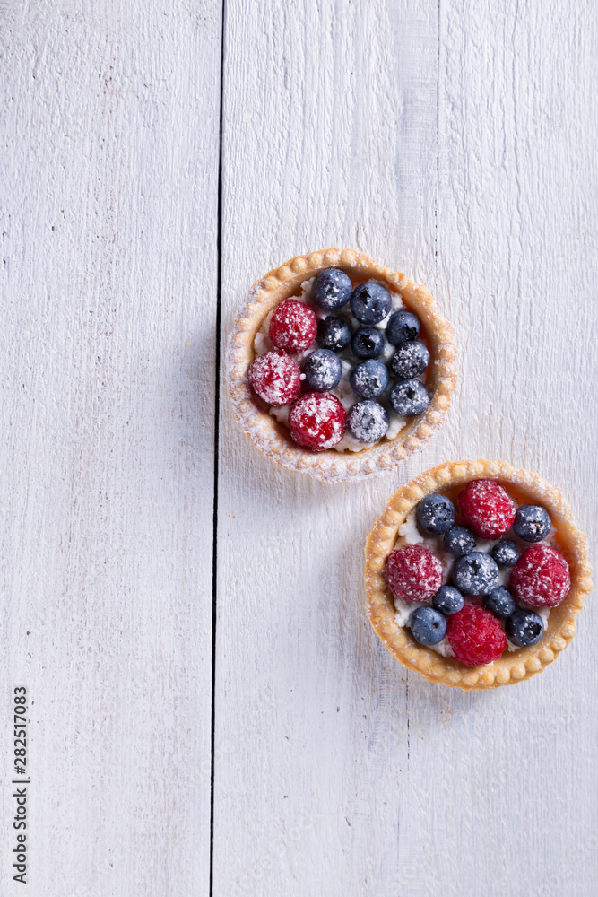 Cakes with fresh fruits on a white wooden background Top view