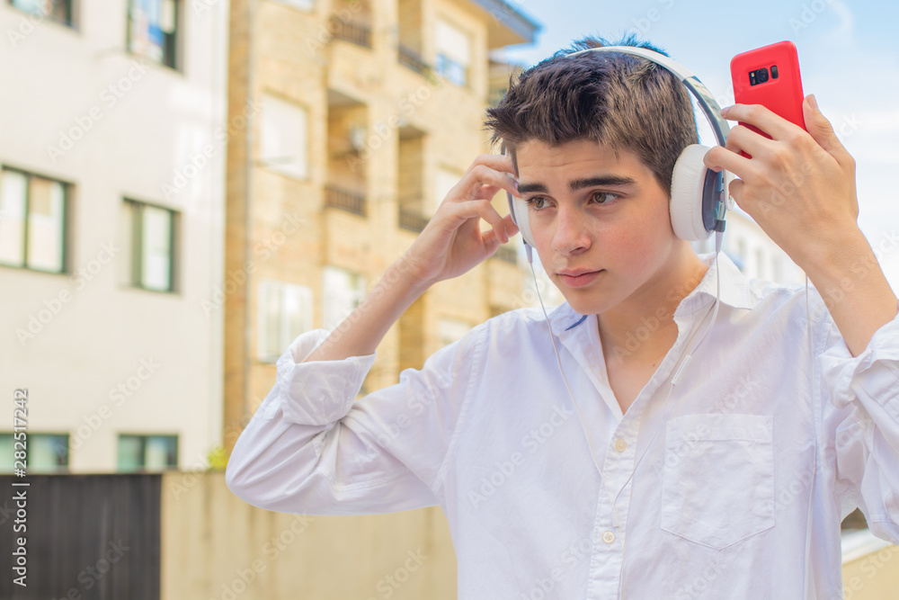 young man with mobile phone and headphones on the city street