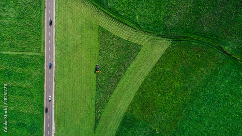 Drone point of view tractor harvesting lush green farmland crop, South Tyrol, Italy photo