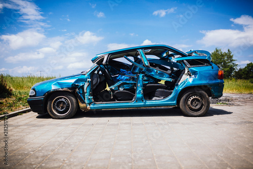 Mangled blue car in sunny parking lot photo