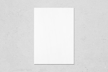 Empty white vertical rectangle poster mockup with soft shadow on neutral light grey concrete wall background. Flat lay, top view