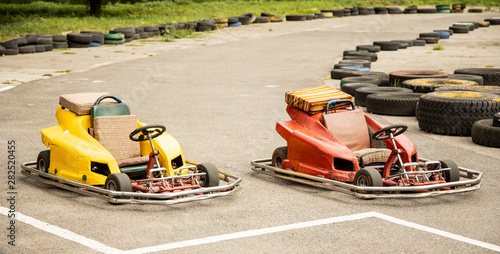 empty kart bolides stay on start of track road fenced by tires and ready for racing 