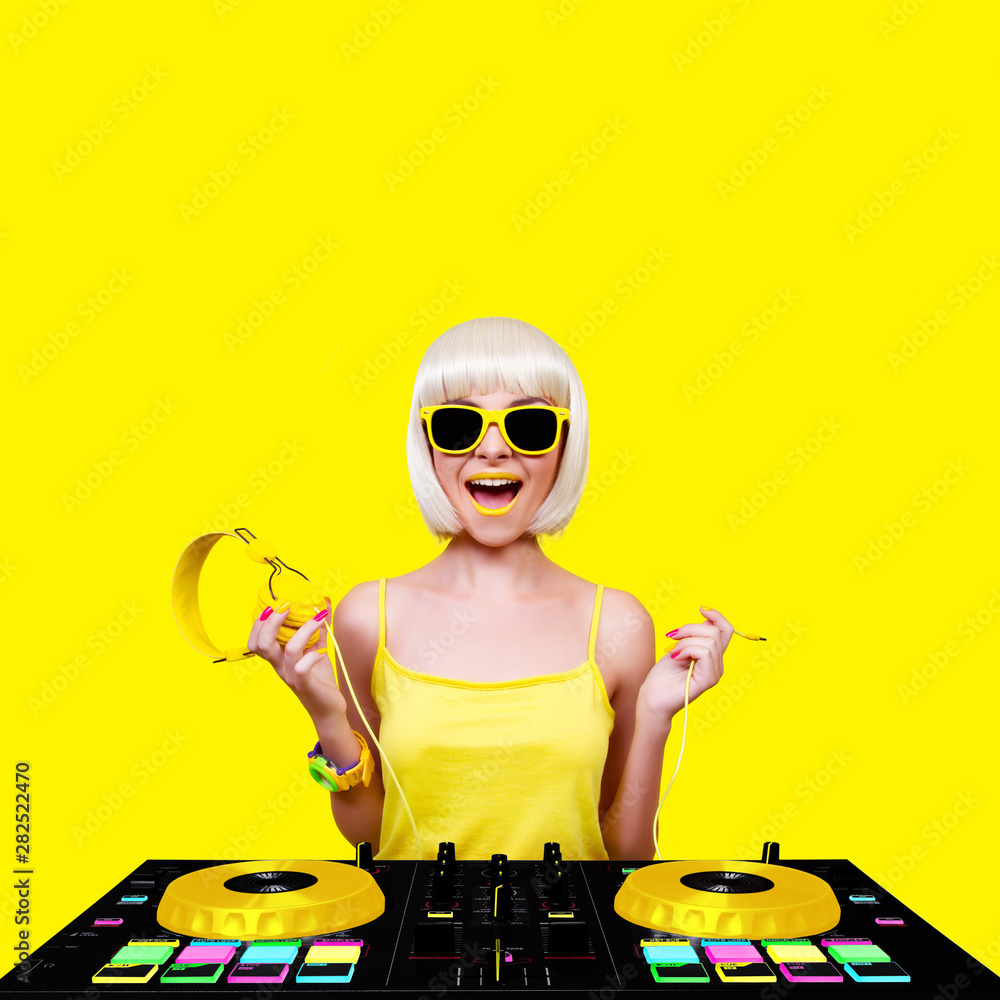 Young sexy woman dj playing music. Headphones and dj mixer on yellow background. Young sexy woman dj playing music. Headphones and dj mixer on yellow background.