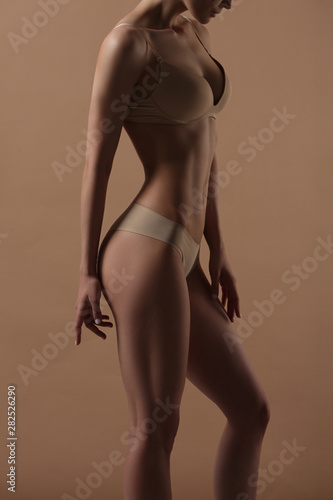 Thin young woman in underwear on beige background © Mirrorstudio