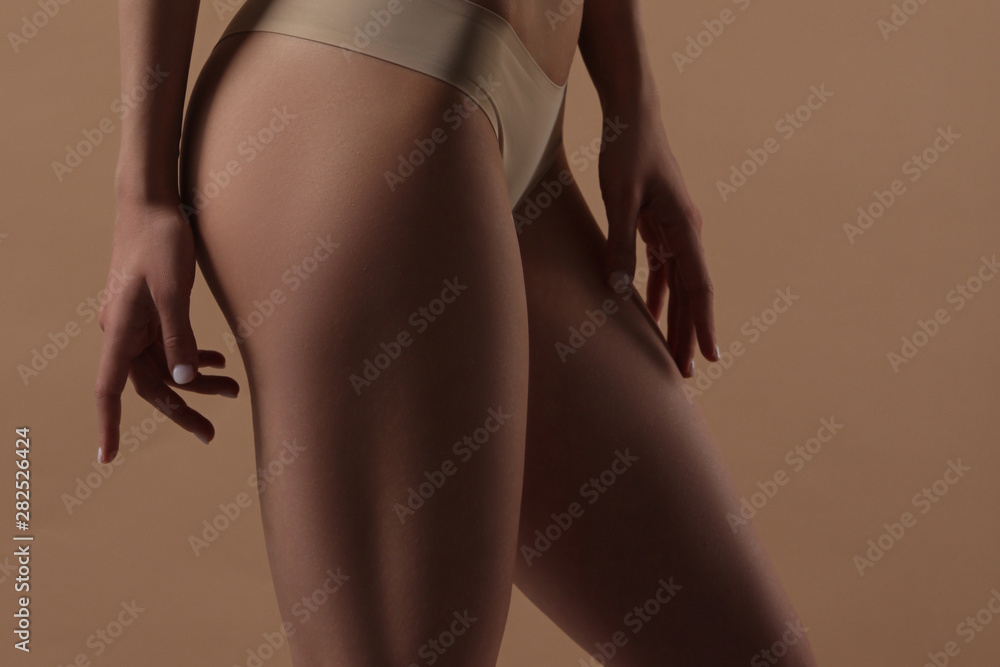 Thin young woman in underwear on beige background - obrazy, fototapety, plakaty 