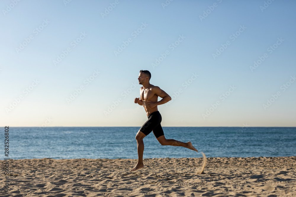 Bare chested man jogging on the beach Bare chested man jogging on the beach