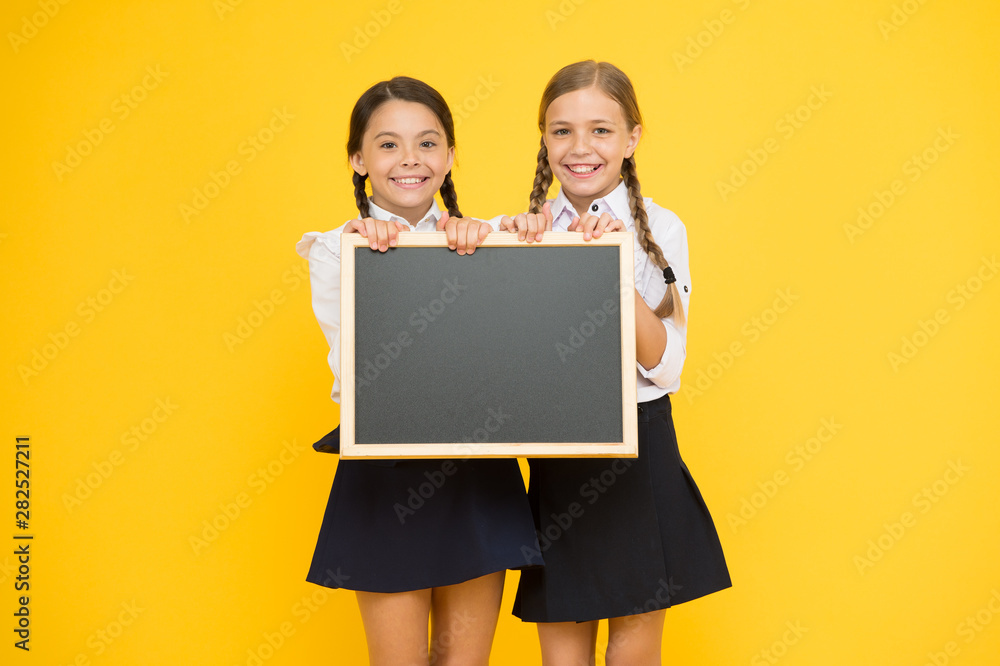 Theres place for your information. Little kids holding blank blackboard for information on yellow background. Small girls with tidy chalkboard for school information. Information for you, copy space Theres place for your information. Little kids holding blank blackboard for information on yellow background. Small girls with tidy chalkboard for school information. Information for you, copy space