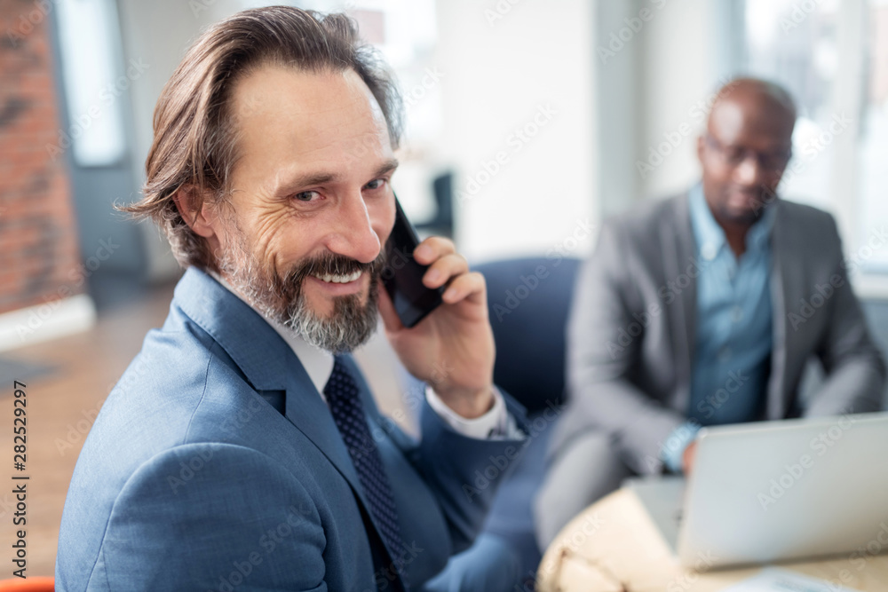 Businessman feeling happy receiving call from wife while working Businessman feeling happy receiving call from wife while working