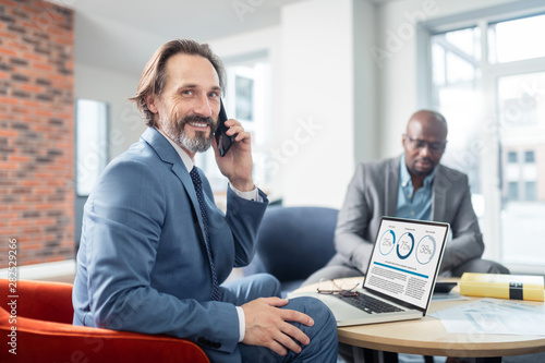 Businessman smiling while receiving call from colleague