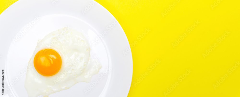 Fried eggs minimal concept on a bright yellow background. Egg yolk on a pan Fried eggs minimal concept on a bright yellow background. Egg yolk on a pan
