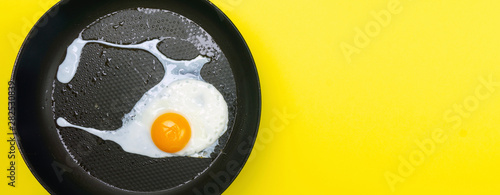 Fried eggs minimal concept on a bright yellow background. Egg yolk on a pan